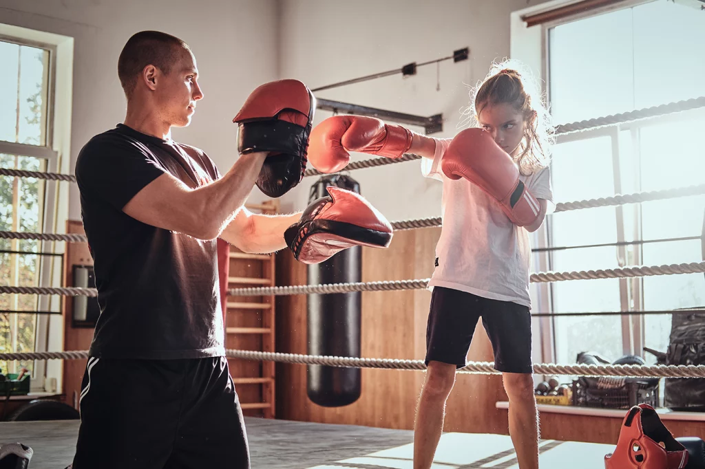 Ein Box-Trainer trainiert ein junges Mädchen.